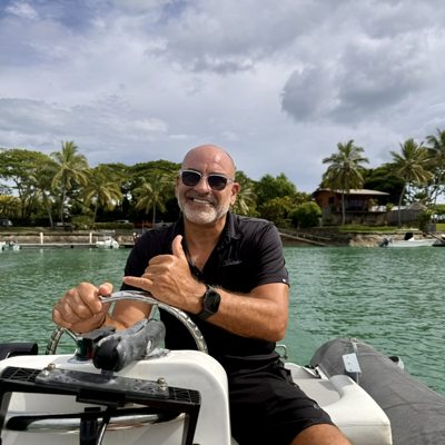 Brian Fabiano driving his dinghy, throwing a shaka